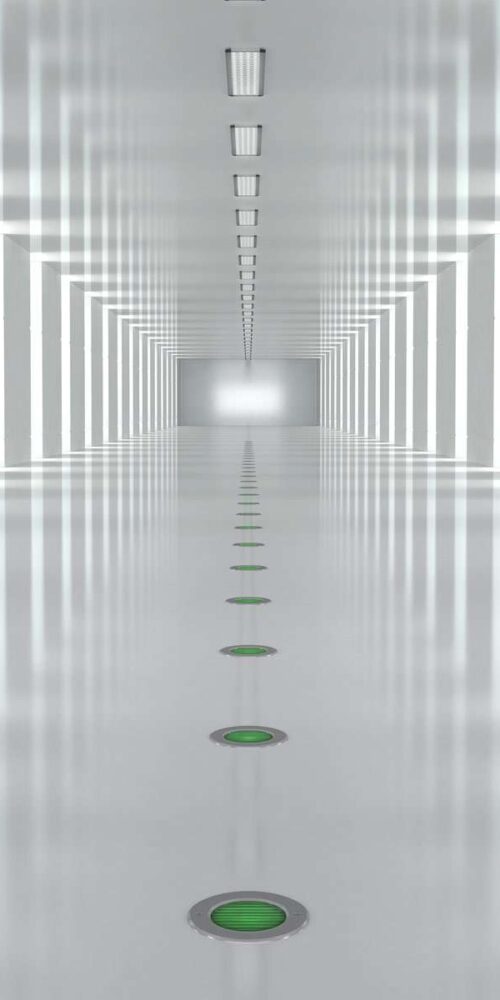 Encastrés de sol verts alignés au centre d’un couloir blanc, en perspective symétrique