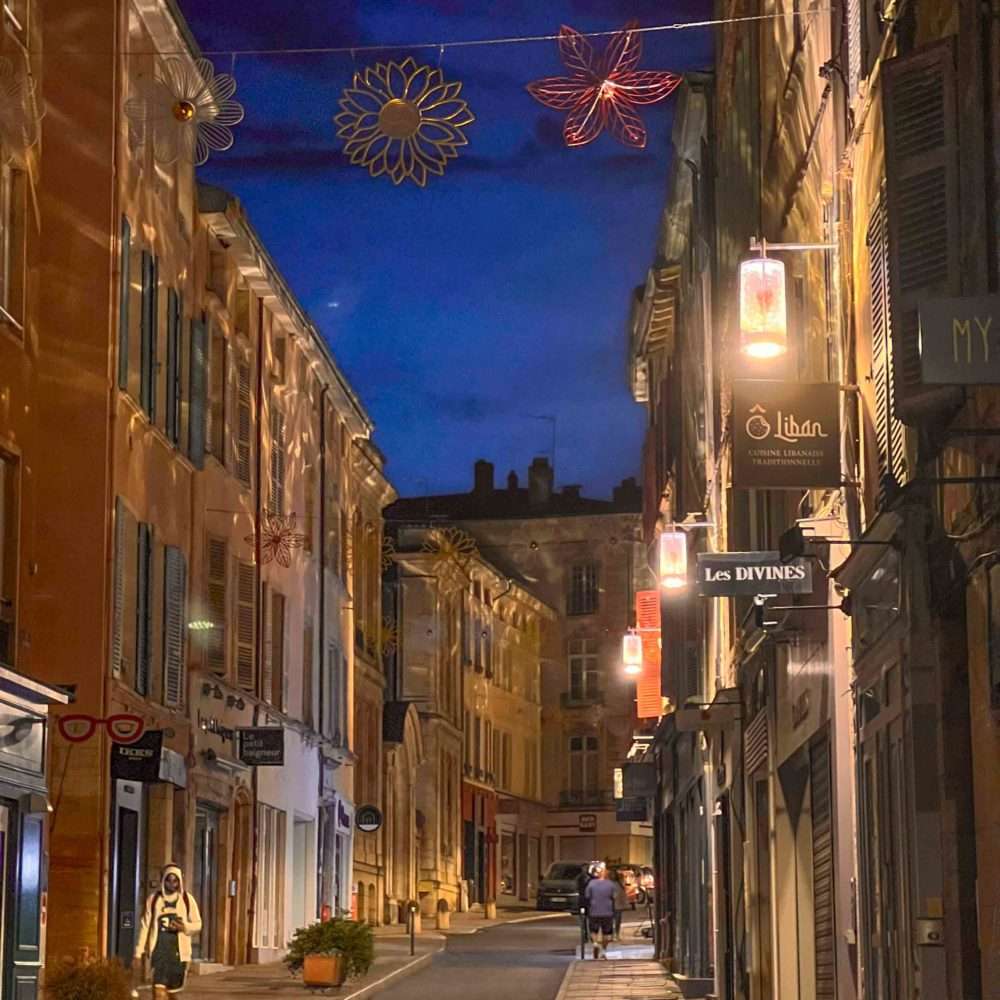Rue commerçante de Mâcon éclairée par les lanternes Leiza