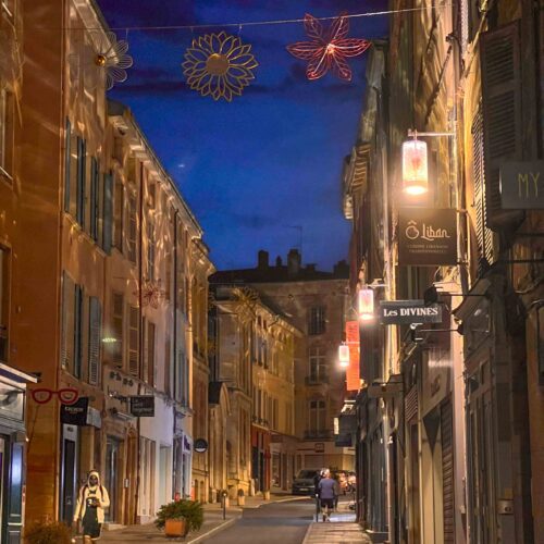 Rue commerçante de Mâcon éclairée par les lanternes Leiza