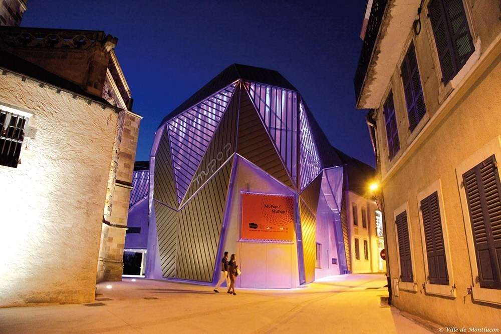 Façades facettées du MuPop éclairées en violet, Montluçon